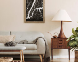 Modern composition of living room interior with brown mock up poster frame, design retro commode, sofa, bookstand, rattan basket with plant and elegant accessories. Template. Stylish home staging.